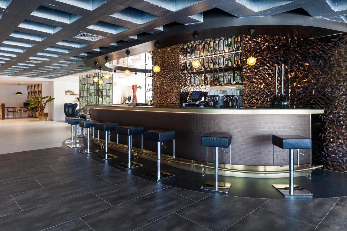 Un bar con taburetes negros en una habitación. en Ibiza Corso Hotel & Spa, en Ibiza
