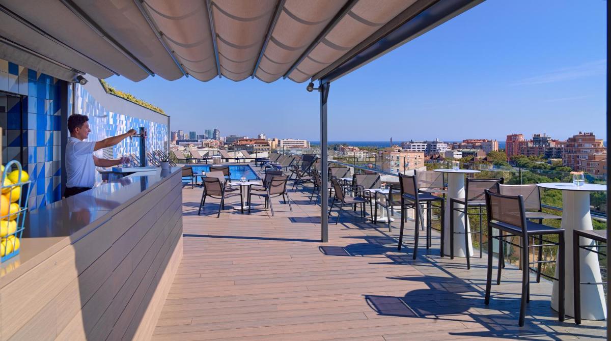 un hombre parado en un bar en un balcón en H10 Marina Barcelona, en Barcelona