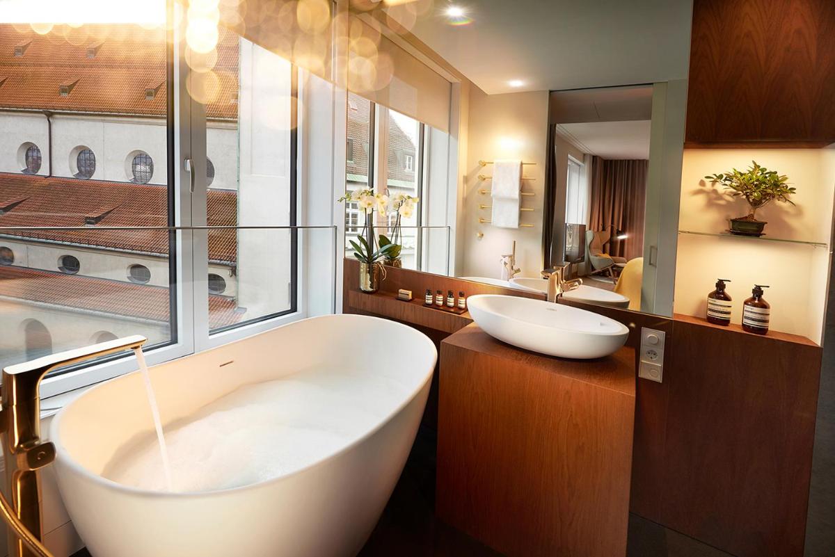 ein Badezimmer mit einer großen weißen Badewanne und einem Waschbecken in der Unterkunft BEYOND by Geisel in München + 37 Fotos ein Badezimmer mit einer großen weißen Badewanne und einem Waschbecken in der Unterkunft BEYOND by Geisel in München + 37 Fotos