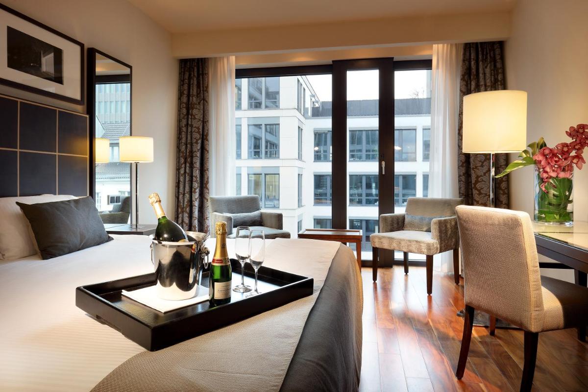 ein Hotelzimmer mit einem Bett und einem Tisch mit Weinflaschen in der Unterkunft Eurostars Berlin in Berlin