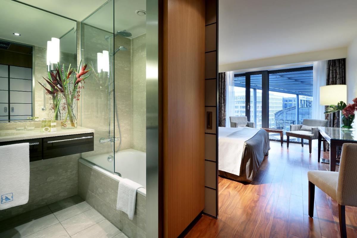 ein Badezimmer mit einer Badewanne und ein Schlafzimmer mit einem Bett in der Unterkunft Eurostars Berlin in Berlin