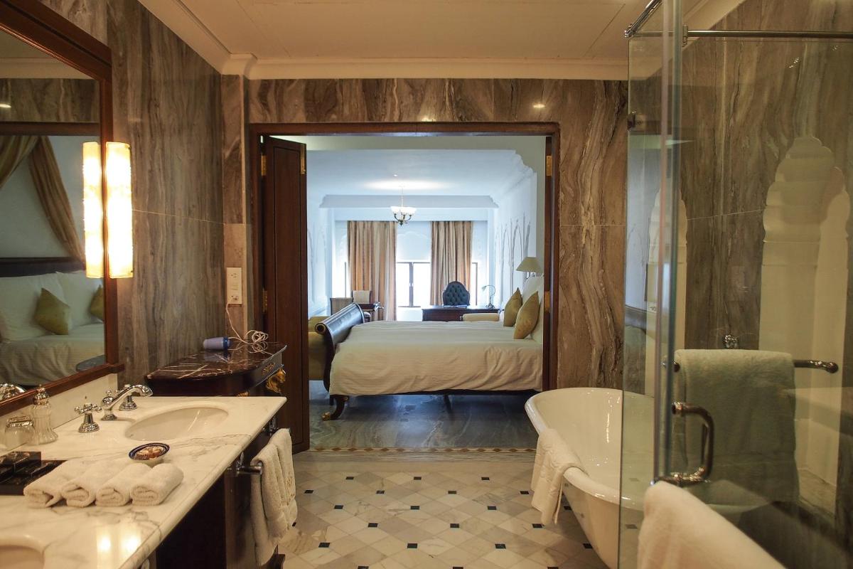 a bathroom with a tub and a bedroom with a bed at The Raj Palace (Small Luxury Hotels of the World) in Jaipur