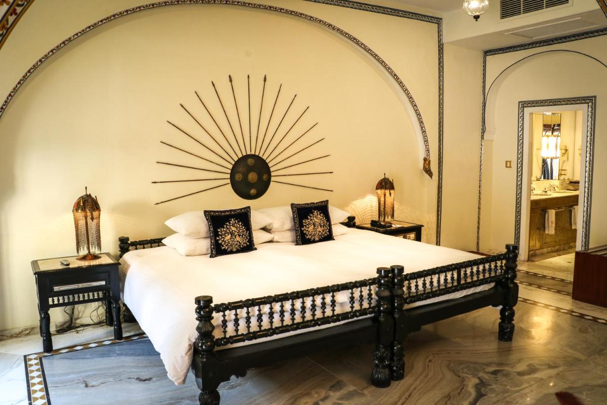 a bedroom with a large bed with a large clock on the wall at The Raj Palace (Small Luxury Hotels of the World) in Jaipur