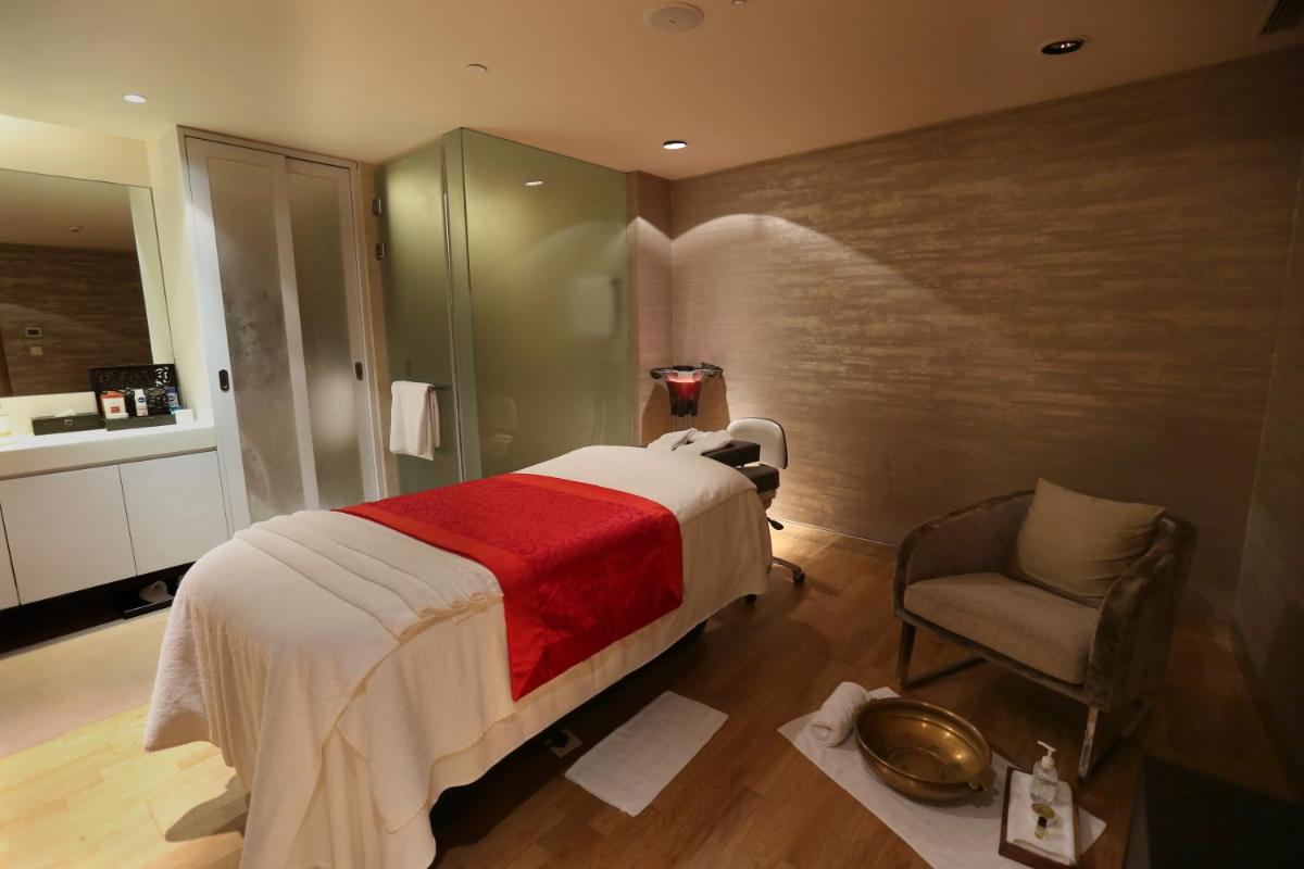 a bedroom with a bed and a chair and a bathroom at Novotel New Delhi Aerocity in New Delhi