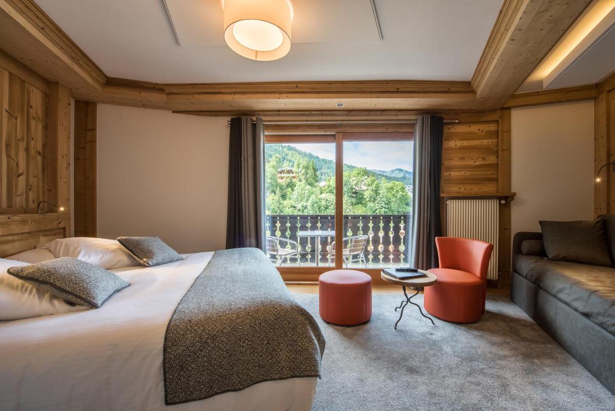 une chambre avec un lit, un canapé et une fenêtre dans l'établissement Hotel le Petit Dru, à Morzine