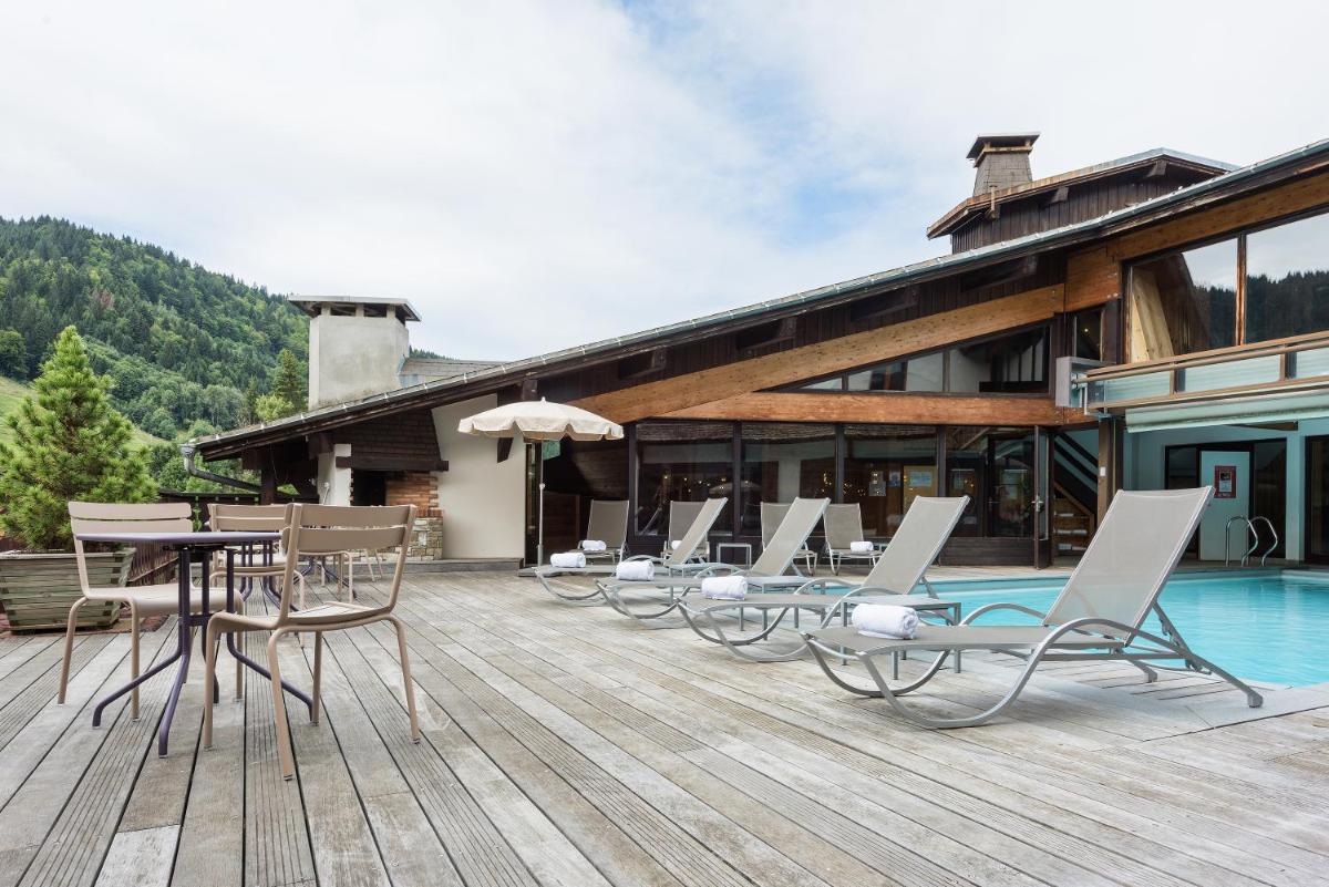 une terrasse avec des chaises et une table et une piscine dans l'établissement Hotel le Petit Dru, à Morzine