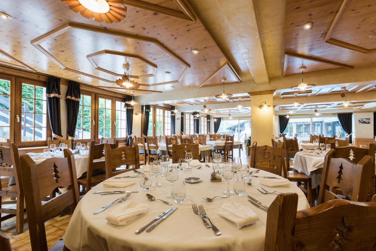 une salle à manger avec tables et chaises avec du linge de table blanc dans l'établissement Hotel le Petit Dru, à Morzine