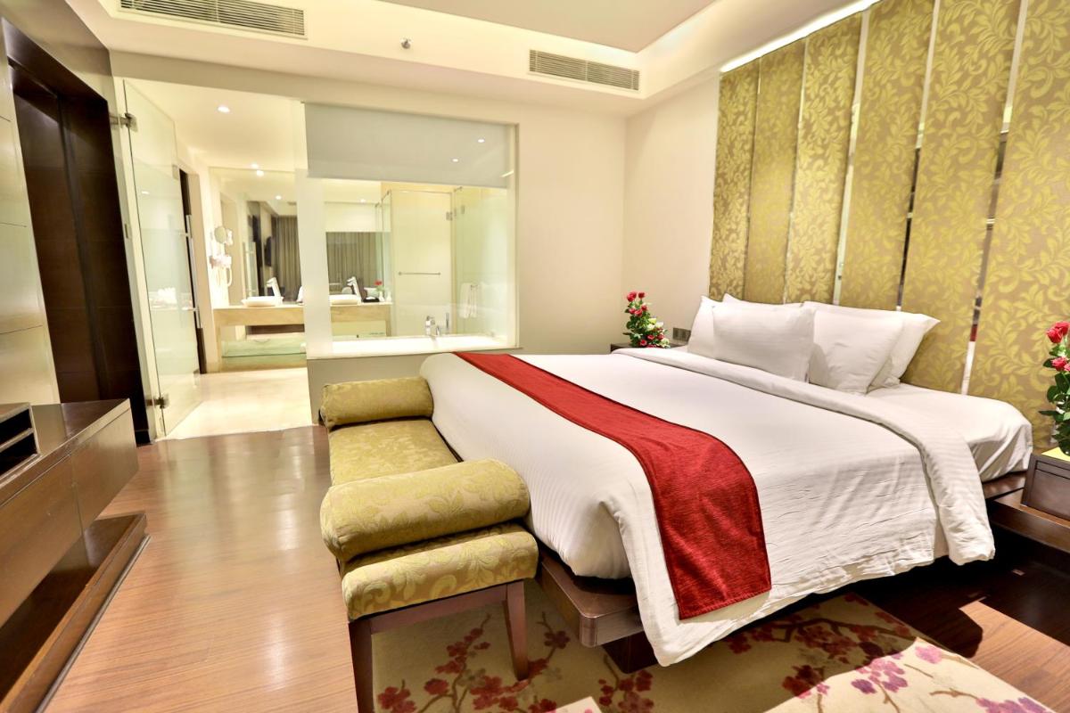 a bedroom with a large bed and a bathroom at Hotel Royal Orchid Jaipur, Tonk Road in Jaipur