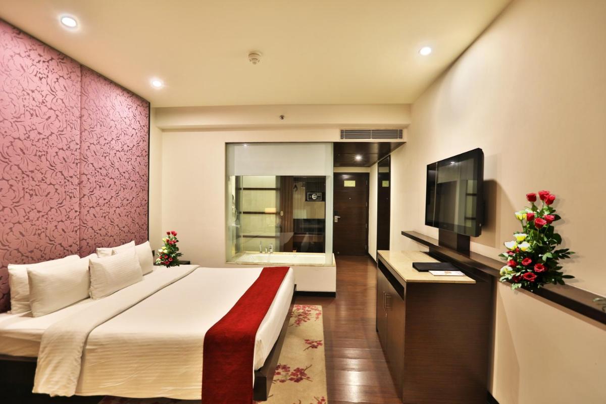 a hotel room with a bed and a flat screen tv at Hotel Royal Orchid Jaipur, Tonk Road in Jaipur