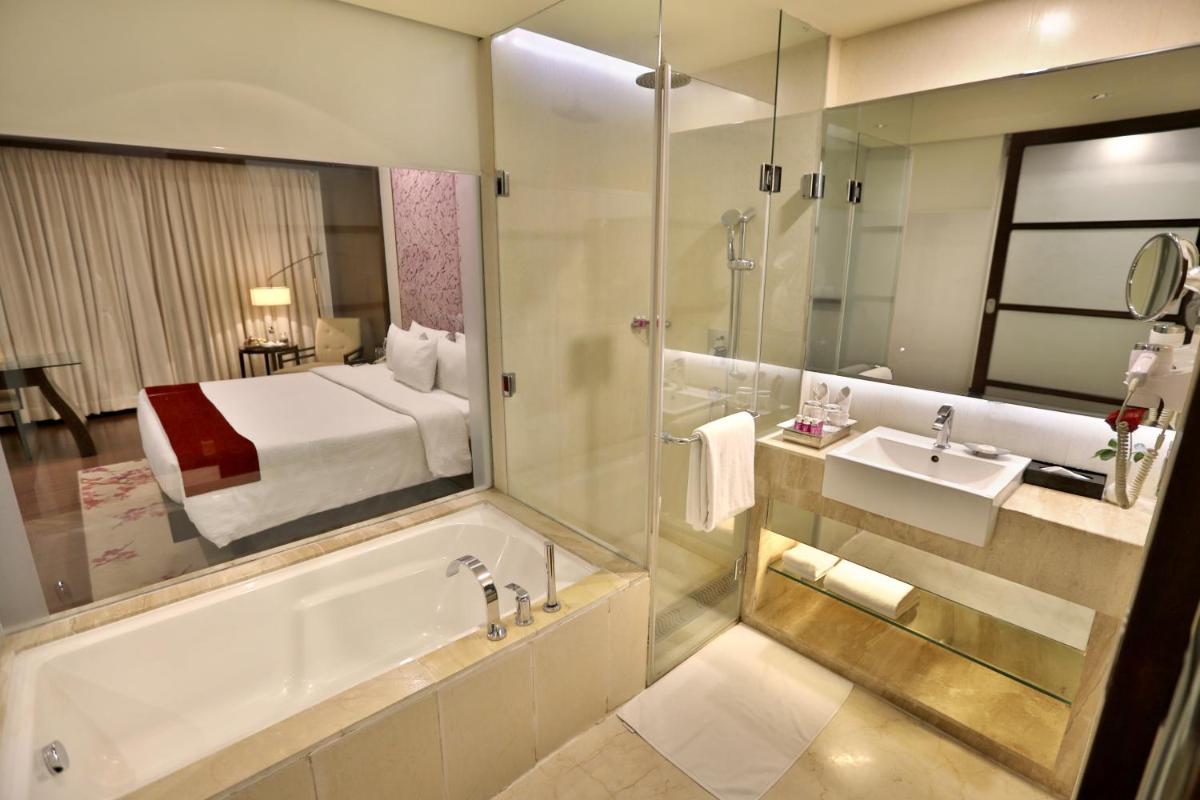 a bathroom with a tub and a sink and a bed at Hotel Royal Orchid Jaipur, Tonk Road in Jaipur