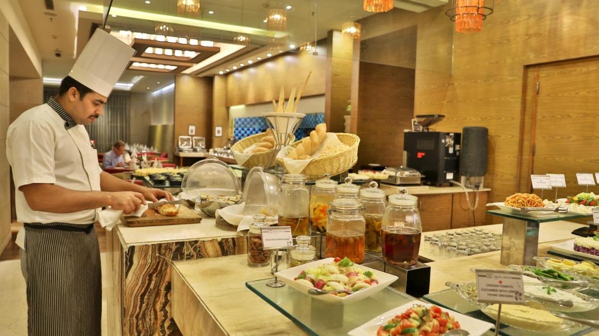 a chef preparing food in a restaurant kitchen at Hotel Royal Orchid Jaipur, Tonk Road in Jaipur