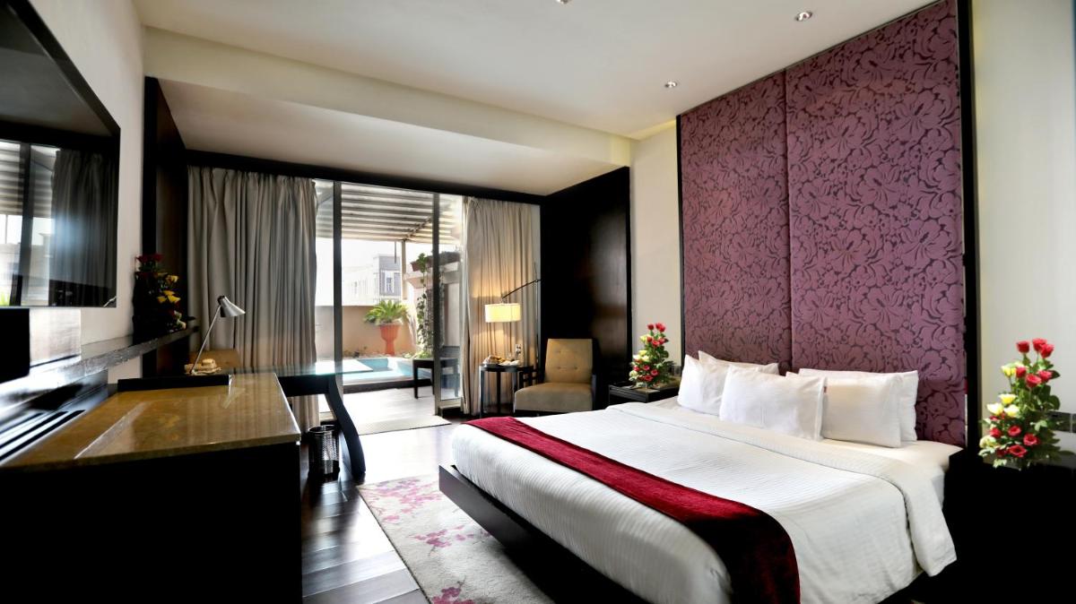 a hotel room with a large bed with a purple wall at Hotel Royal Orchid Jaipur, Tonk Road in Jaipur
