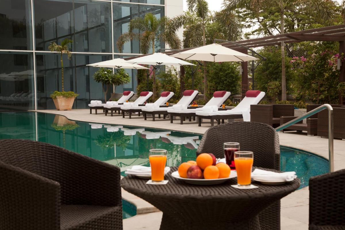 a table with a bowl of fruit on it next to a pool at Radisson Blu Plaza Hotel Hyderabad Banjara Hills in Hyderabad a table with a bowl of fruit on it next to a pool at Radisson Blu Plaza Hotel Hyderabad Banjara Hills in Hyderabad