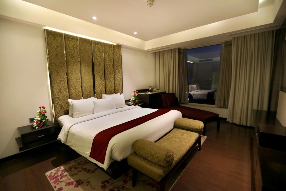 a hotel room with a large bed and a window at Hotel Royal Orchid Jaipur, Tonk Road in Jaipur