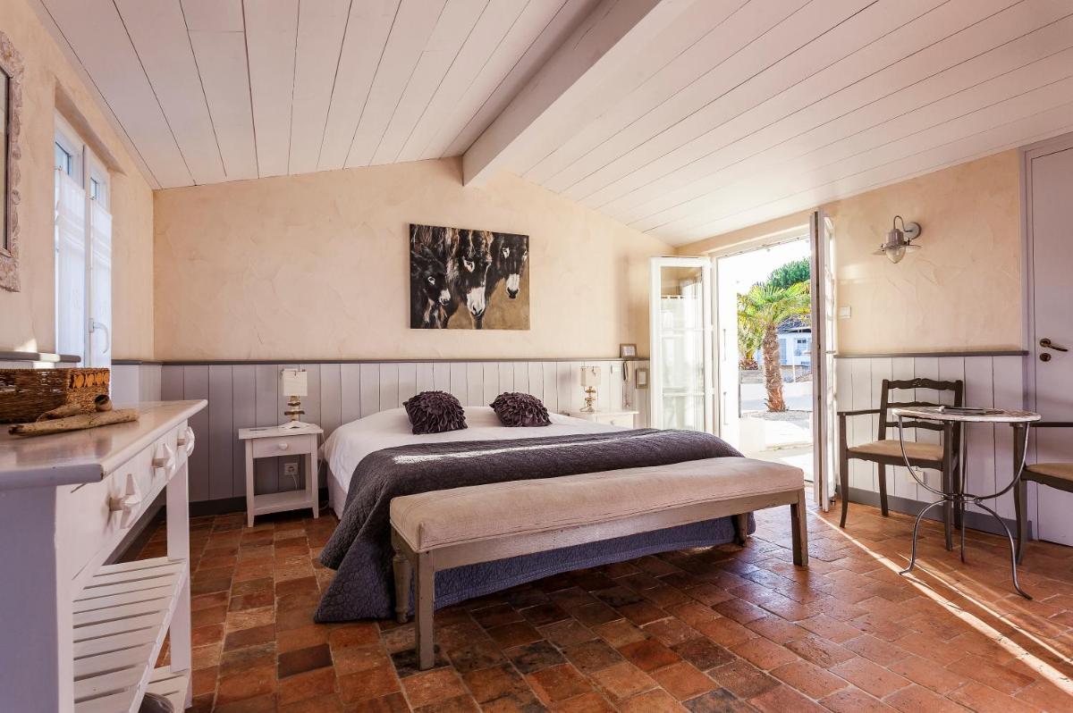 une chambre avec un lit et une table dans une pièce dans l'établissement Hotel Les Bois Flottais, au Bois-Plage-en-Ré