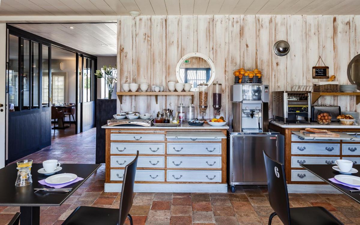 - une cuisine avec des murs en bois, une table et des chaises dans l'établissement Hotel Les Bois Flottais, au Bois-Plage-en-Ré