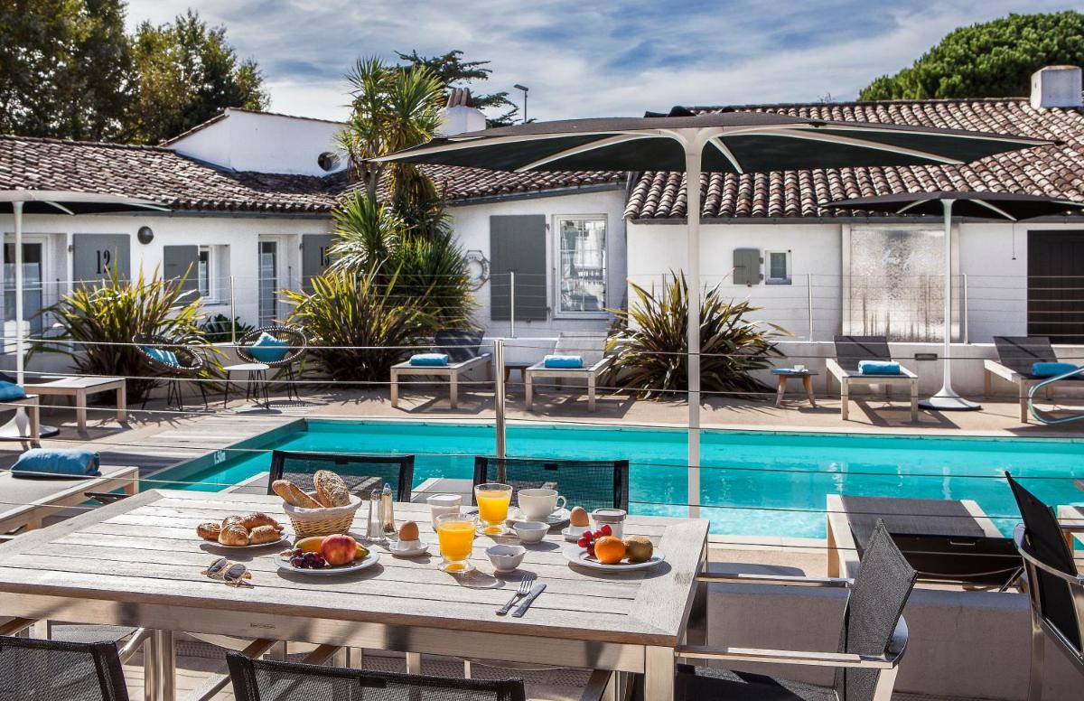 une table avec de la nourriture dessus à côté d'une piscine dans l'établissement Hotel Les Bois Flottais, au Bois-Plage-en-Ré