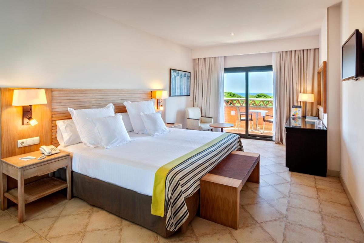 Una habitación de hotel con una cama grande y un balcón. en Barceló Punta Umbría Beach Resort, en Punta Umbría