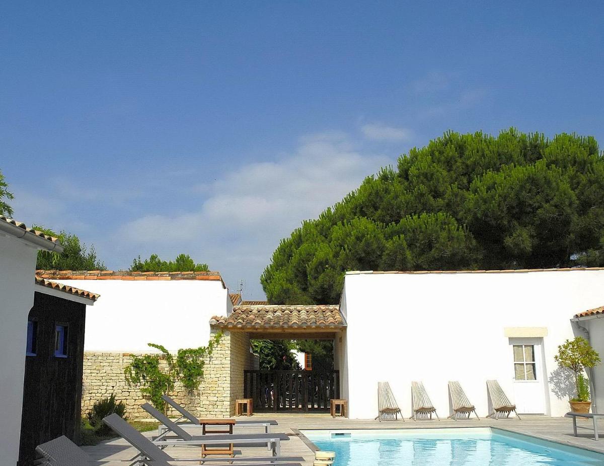 une piscine avec des chaises et un bâtiment dans l'établissement Hotel L'Océan, au Bois-Plage-en-Ré