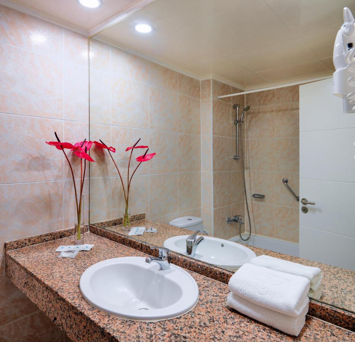 Un baño con lavabo, bañera y espejo. en Relaxia Beverly Park, en Playa del Inglés