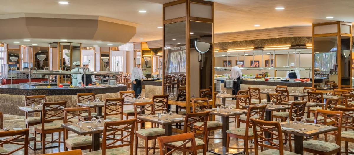 Un restaurante con mesas y sillas y un bar. en Relaxia Beverly Park, en Playa del Inglés
