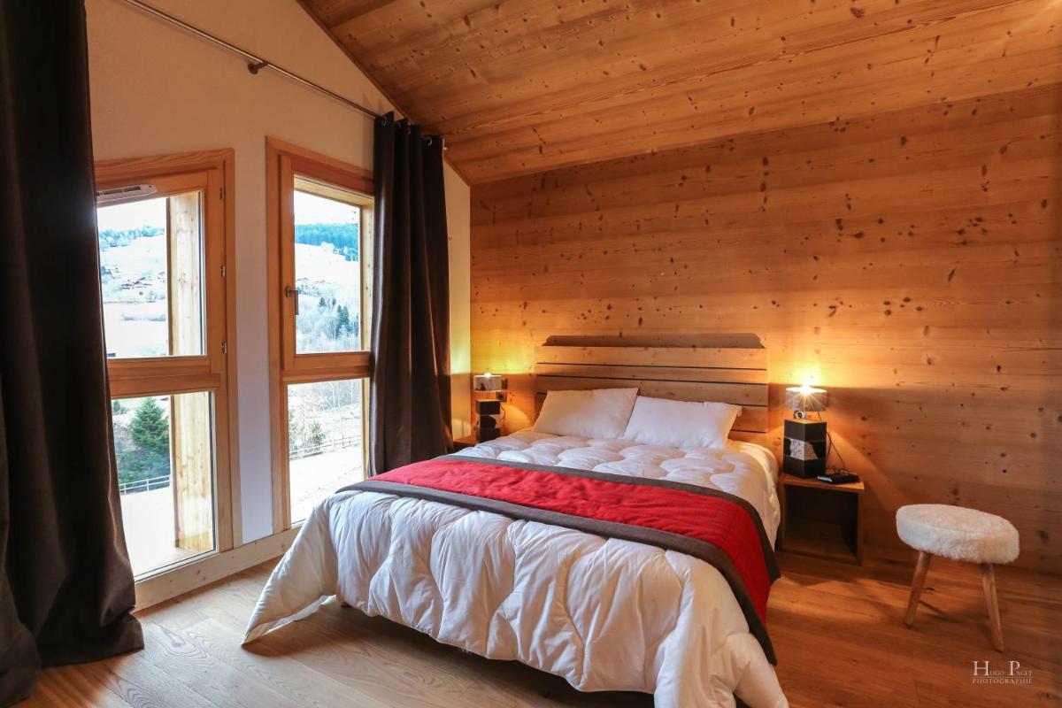 une chambre avec un lit dans une pièce aux murs en bois dans l'établissement TERRESENS - Les Fermes du Mont-Blanc, à Combloux 89 autres photos