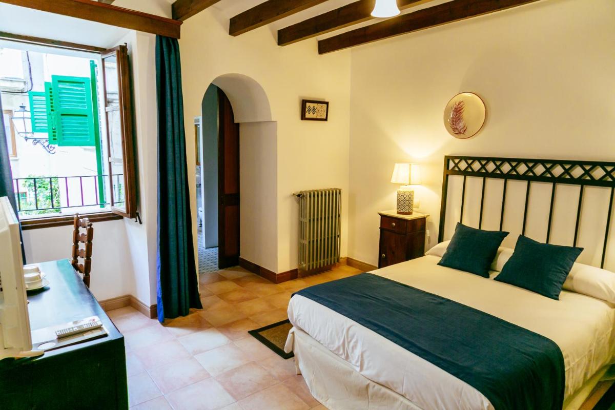 Un dormitorio con una cama grande y una ventana. en Hotel El Guía, en Sóller