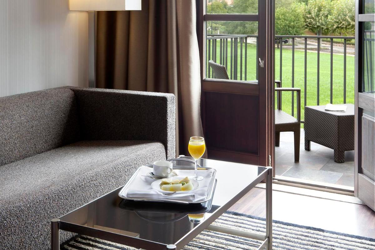 sala de estar con sofá y mesa de cristal con una bebida en Eurostars Vila de Allariz Hotel Balneario, en Allariz