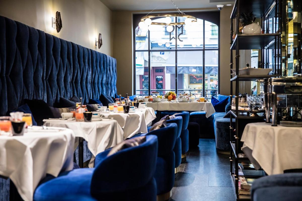 un restaurant avec deux tables avec des nappes blanches dans l'établissement Monsieur Cadet Hotel & Spa, à Paris
