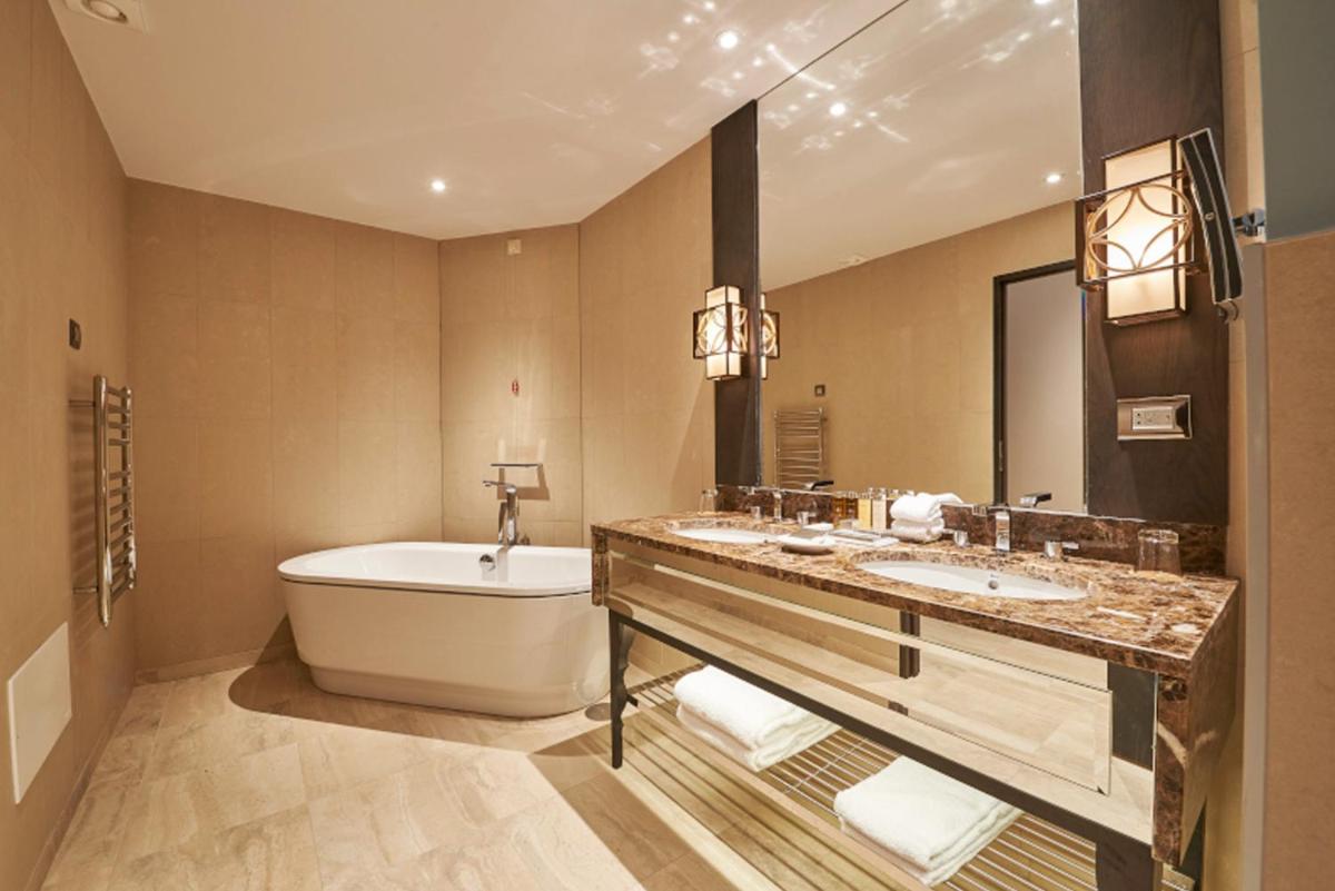 um banheiro com duas pias, uma banheira e um vaso sanitário em Dona Filipa Hotel no Vale do Lobo