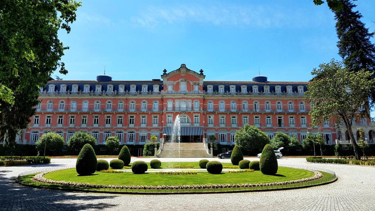 um grande edifício vermelho com um jardim em frente em Vidago Palace em Vidago