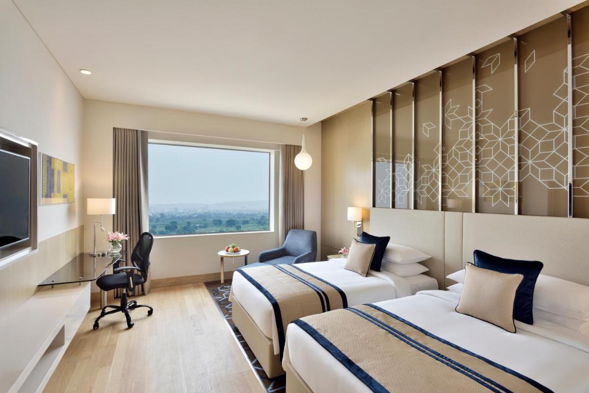 a hotel room with two beds and a television at Radisson Gurugram Udyog Vihar in Gurgaon a hotel room with two beds and a television at Radisson Gurugram Udyog Vihar in Gurgaon