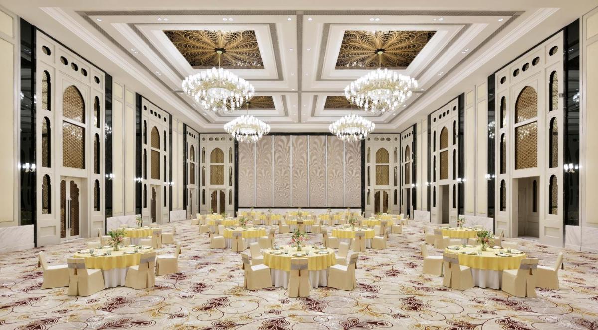 a large banquet hall with tables and chandeliers at The Leela Palace Jaipur in Jaipur