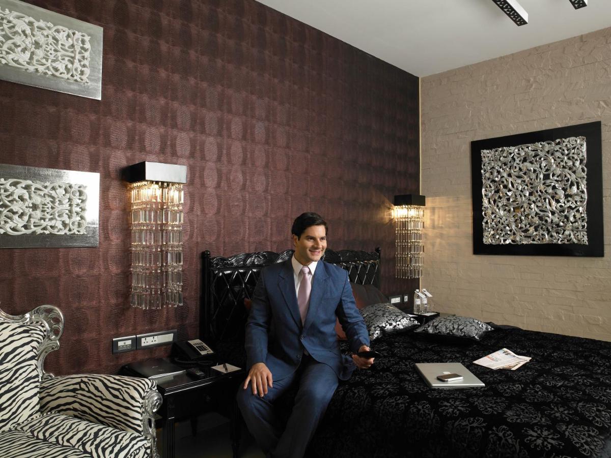 a man in a suit sitting on a bed at The Zuri Whitefield Bengaluru in Bengaluru