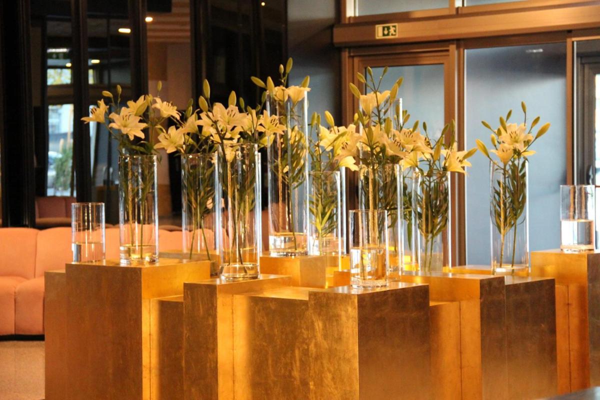 um grupo de vasos cheios de flores amarelas sobre uma mesa em Aurea Fatima Hotel Congress & Spa em Fátima