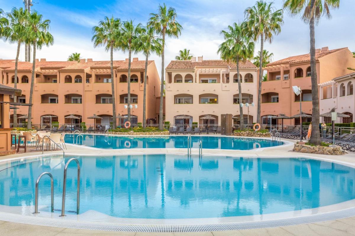 una gran piscina con palmeras frente a un edificio en Los Amigos Beach Club, en La Cala de Mijas