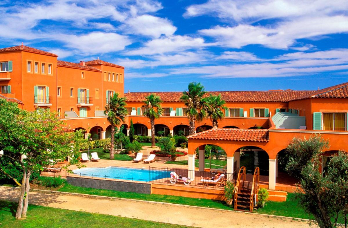 un bâtiment orange avec une piscine et un complexe dans l'établissement Palmyra Golf Hotel & Spa, au Cap d'Agde
