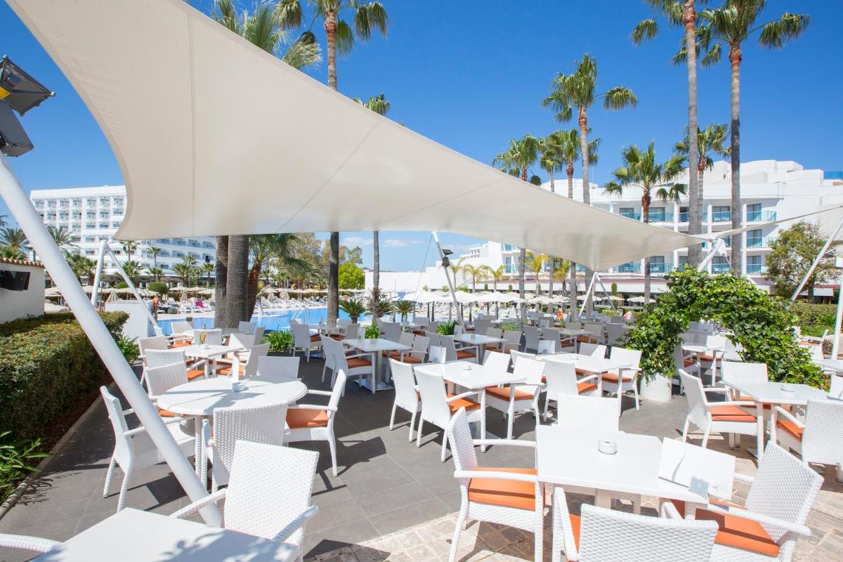 un restaurante con mesas y sillas blancas y una piscina en Hipotels Cala Millor Park, en Cala Millor