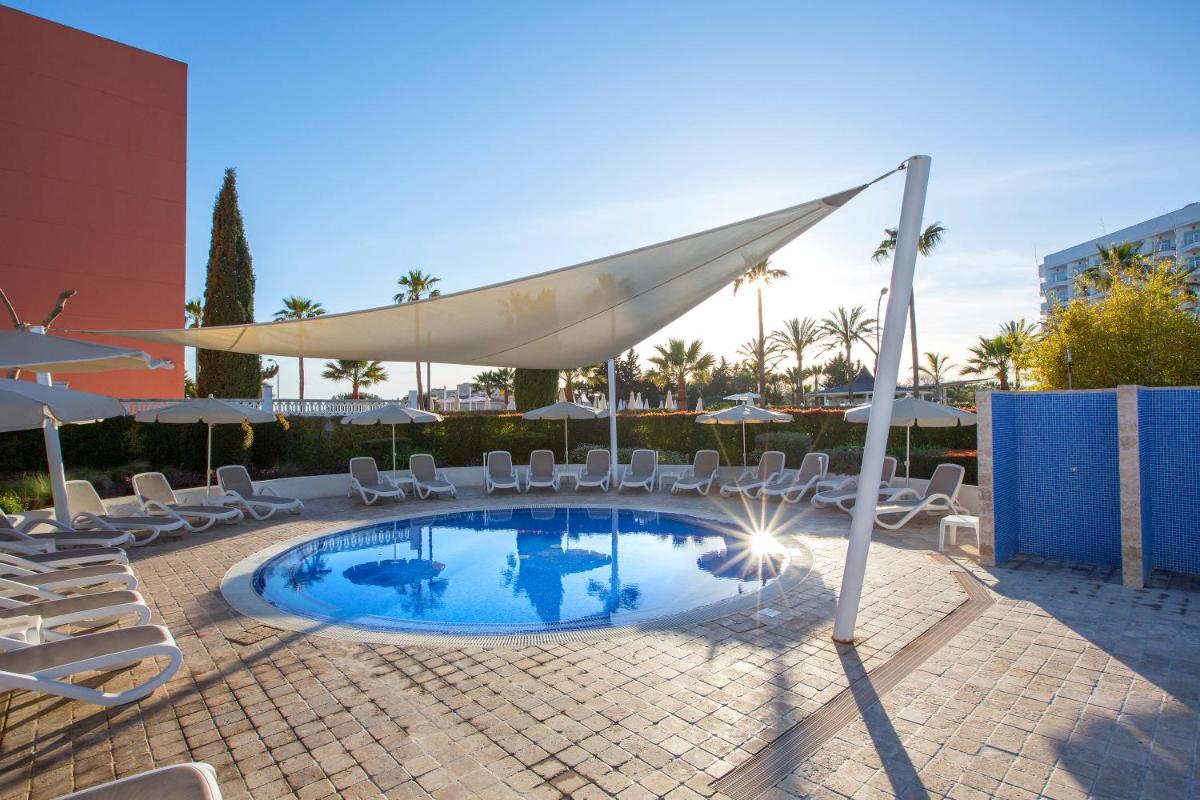 Una piscina con sillas y sombrillas en un patio. en Hipotels Cala Millor Park, en Cala Millor