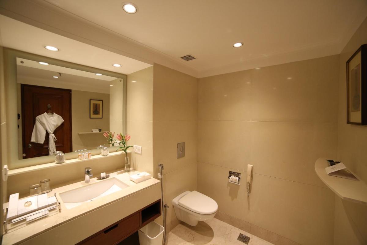 a bathroom with a sink and a toilet and a mirror at Jaypee Palace Hotel in Agra