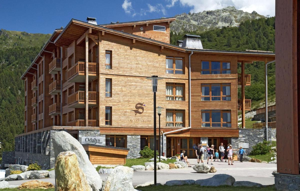 - un grand bâtiment en bois avec des personnes se déplaçant devant dans l'établissement Résidence Prestige Odalys Edenarc, à Arc 1800