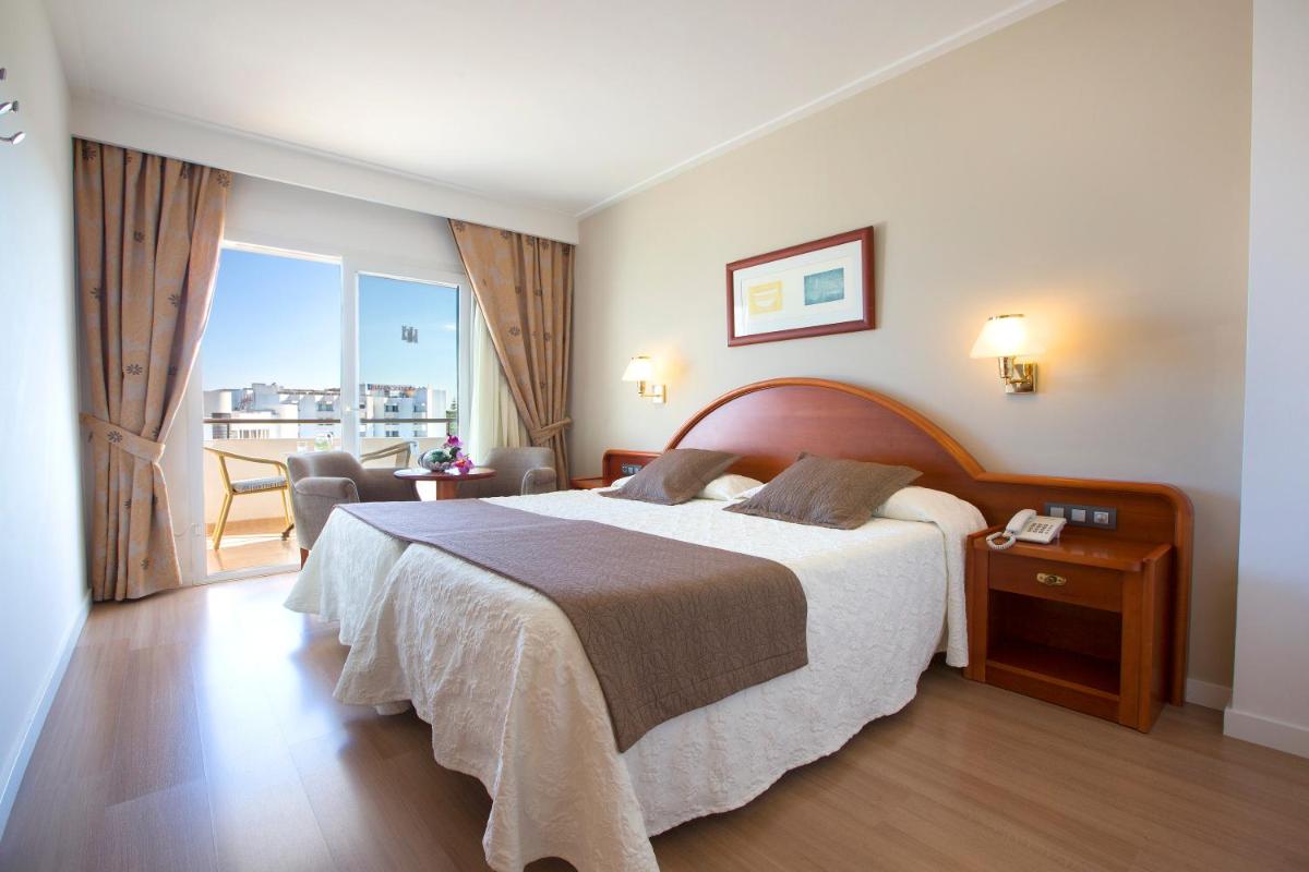 Una habitación de hotel con una cama grande y un balcón. en Hipotels Hipocampo Playa, en Cala Millor