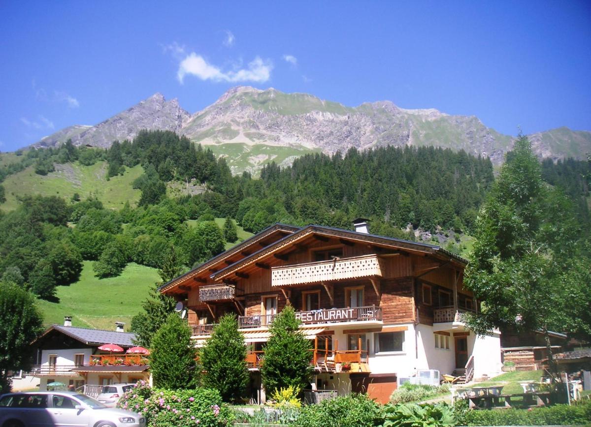 une grande maison en bois avec des montagnes en arrière-plan dans l'établissement Apart'hotel & Spa "La Destière", à La Giettaz