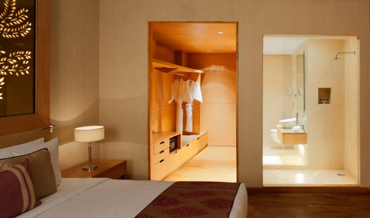a bedroom with a bed and a bathroom with a mirror at Radisson Blu Hotel New Delhi Dwarka in New Delhi a bedroom with a bed and a bathroom with a mirror at Radisson Blu Hotel New Delhi Dwarka in New Delhi