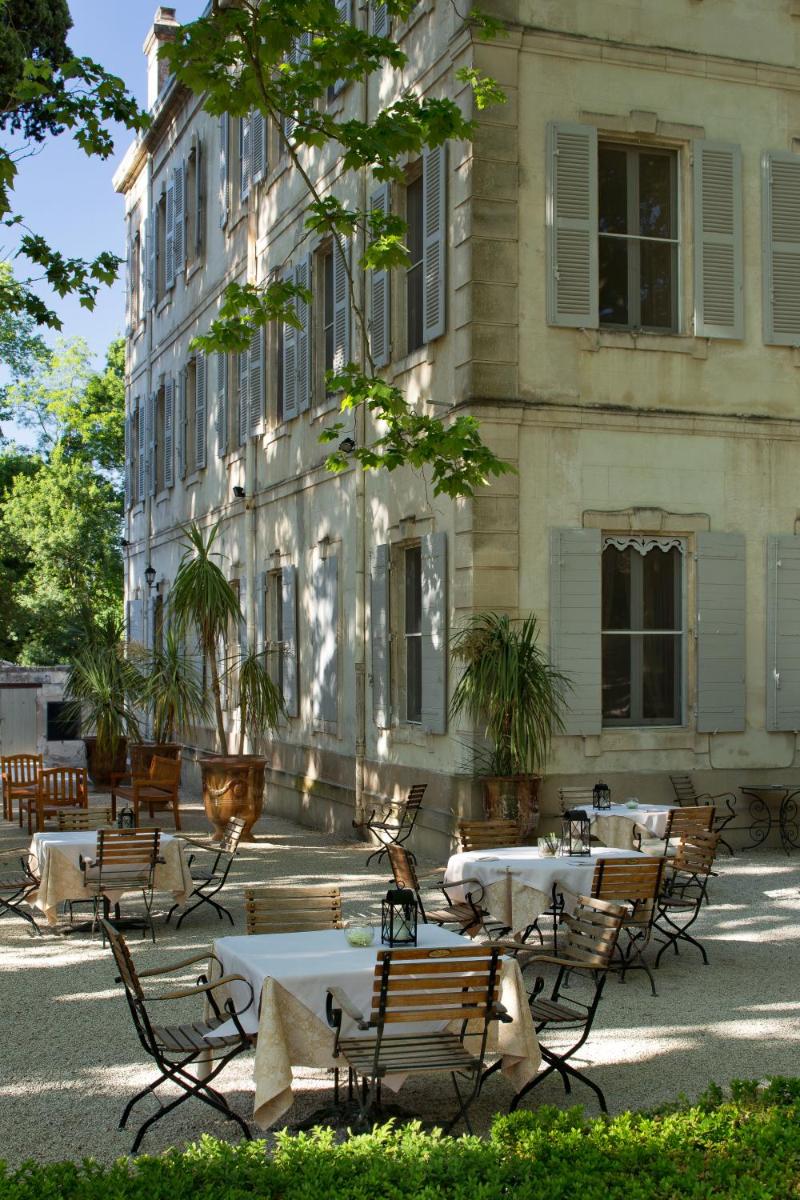 un groupe de tables et de chaises devant un bâtiment dans l'établissement Hotel Château Des Alpilles, à Saint-Rémy-de-Provence