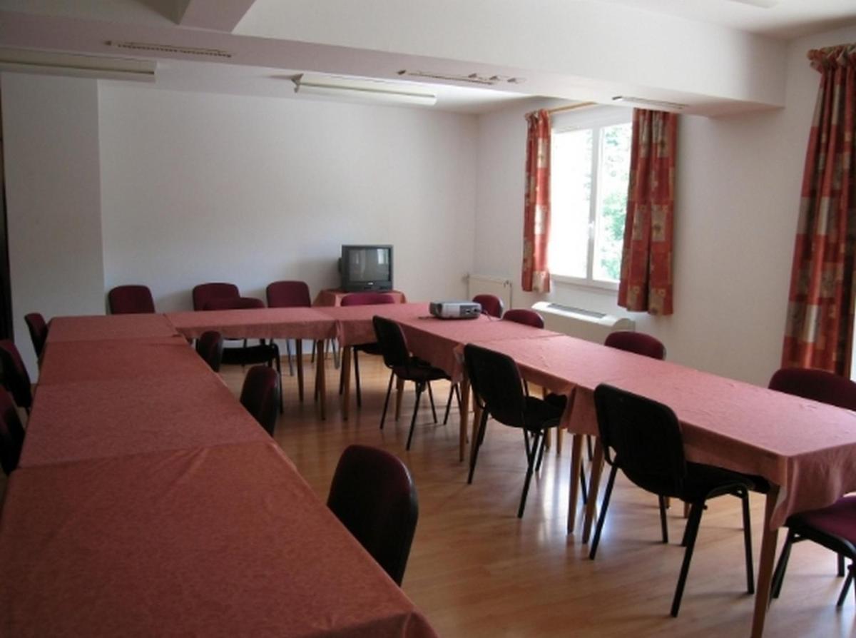 une pièce avec des tables et des chaises et une télévision dans l'établissement Hôtel du Bout du Monde, à Saint-Flour