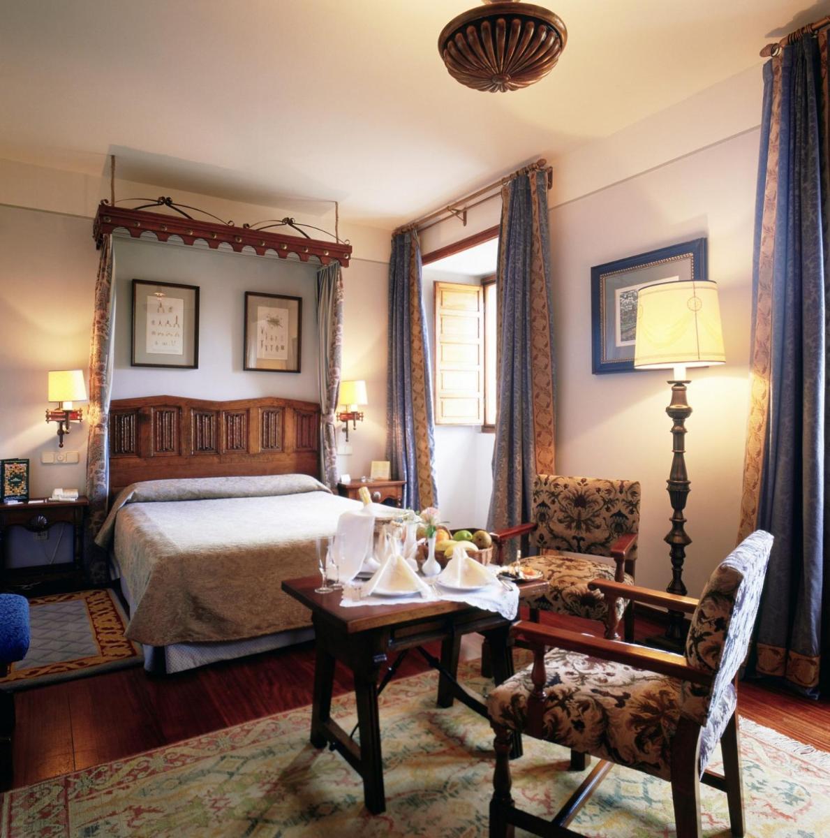 Un dormitorio con una cama, una mesa y una silla. en Parador de Santiago - Hostal Reis Catolicos, en Santiago de Compostela