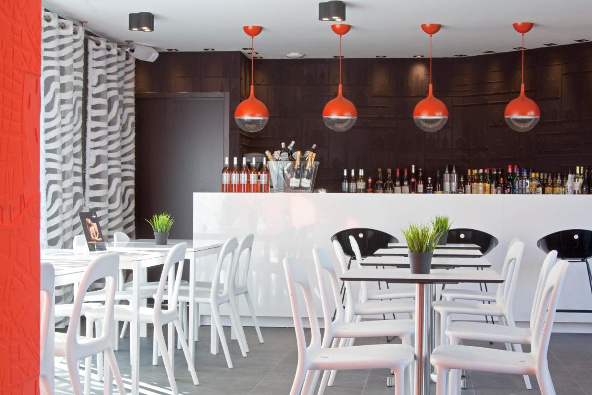 un restaurant avec des chaises blanches et un bar dans l'établissement Hôtel De L'octroi, à Carcassonne