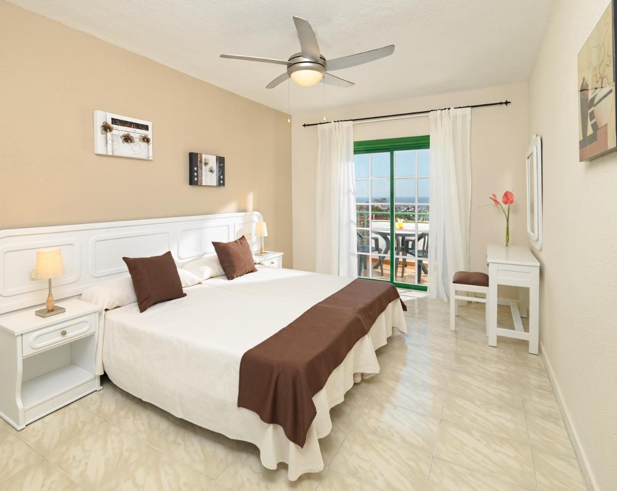 Un dormitorio con una cama grande y un balcón. en Regency Torviscas Apartments and Suites, en Adeje