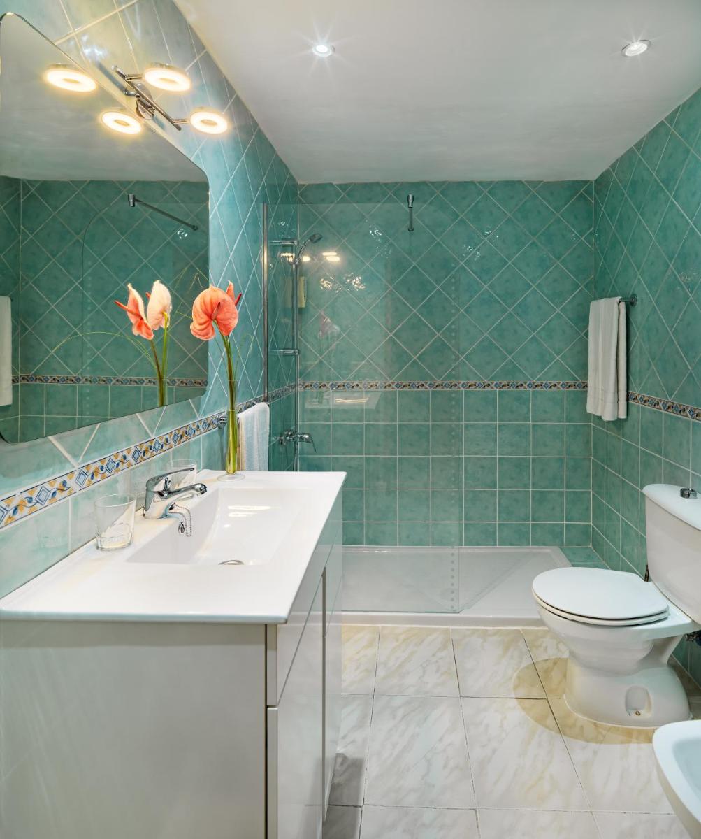 Un baño con lavabo, inodoro y espejo. en Regency Torviscas Apartments and Suites, en Adeje